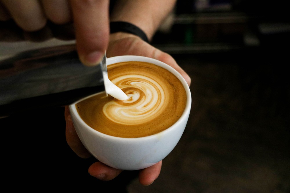 persona poniendo leche en un café